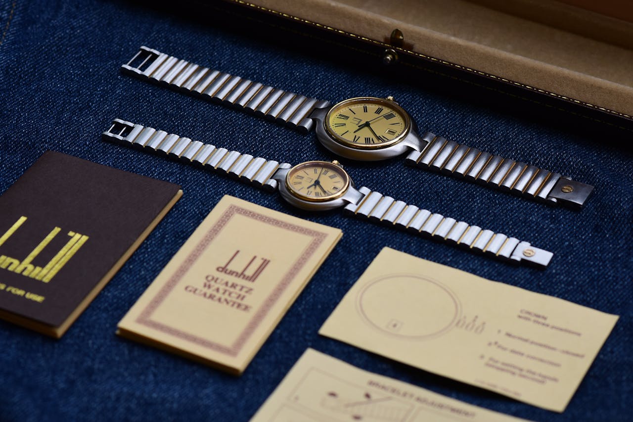Pair of vintage wristwatches with accessories on denim fabric.